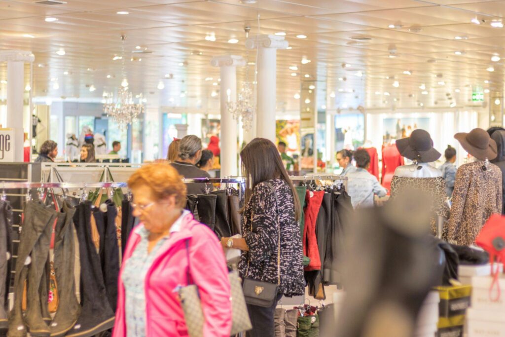 Shoppers browsing clothing racks inside a busy retail store with bright lighting