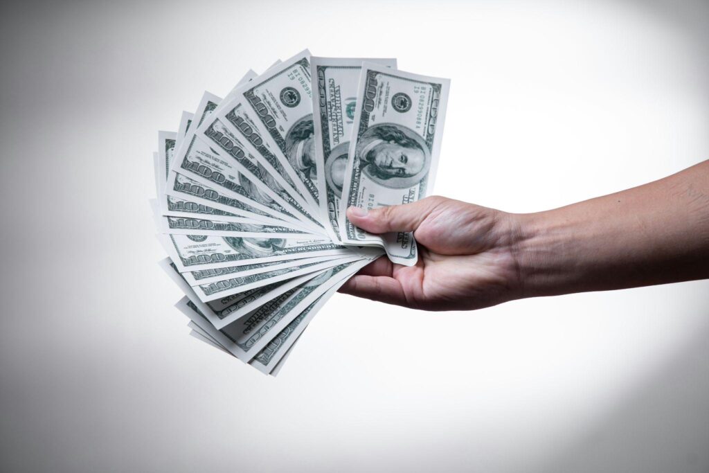 Owner holding fanned cash representing the higher uptime and surcharge revenue that follow when businesses switch ATM provider