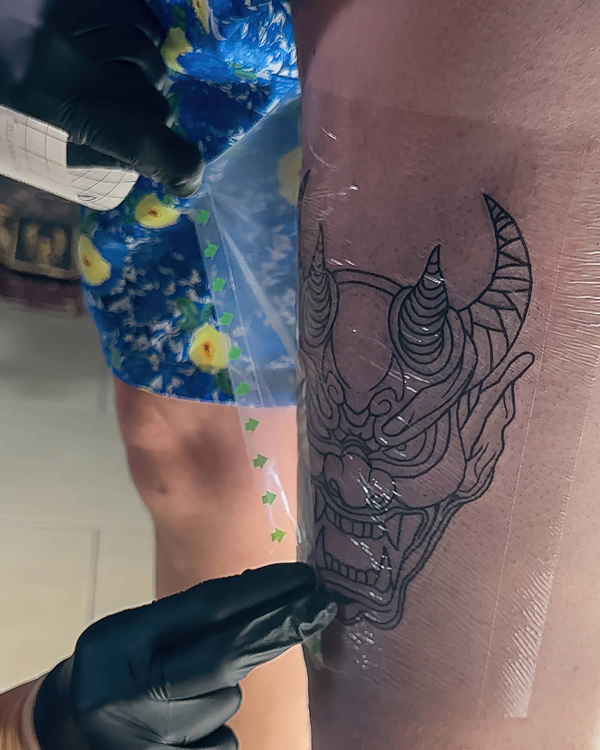 Tattoo covered in second skin, artist making sure it is pressed well on the skin. The tattoo healing process of the aftercare has started.