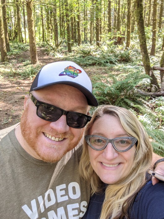 Ben and Emily standing in the middle of a wooded parcel of land that they just bought.
