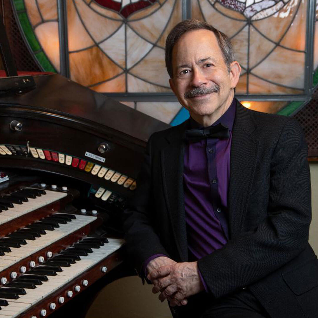 Organist Andrew Rogers leaning against an organ