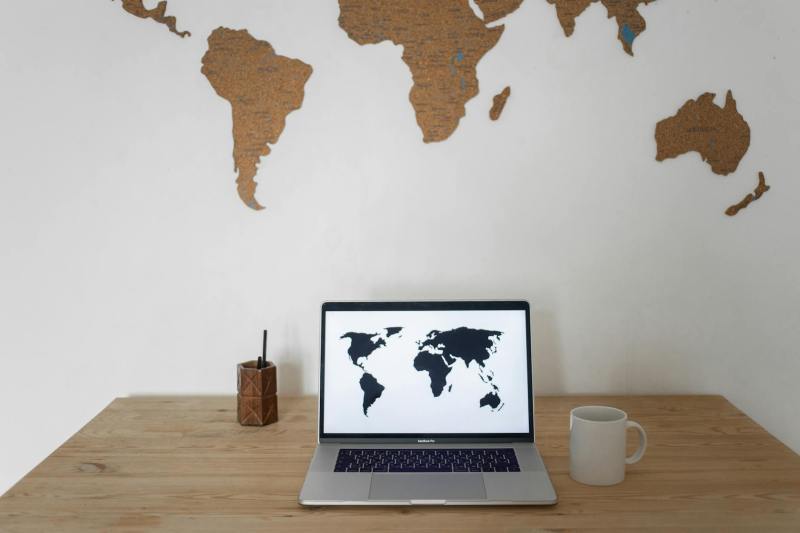 world map on wall and laptop near cup and container | how to start a travel fund