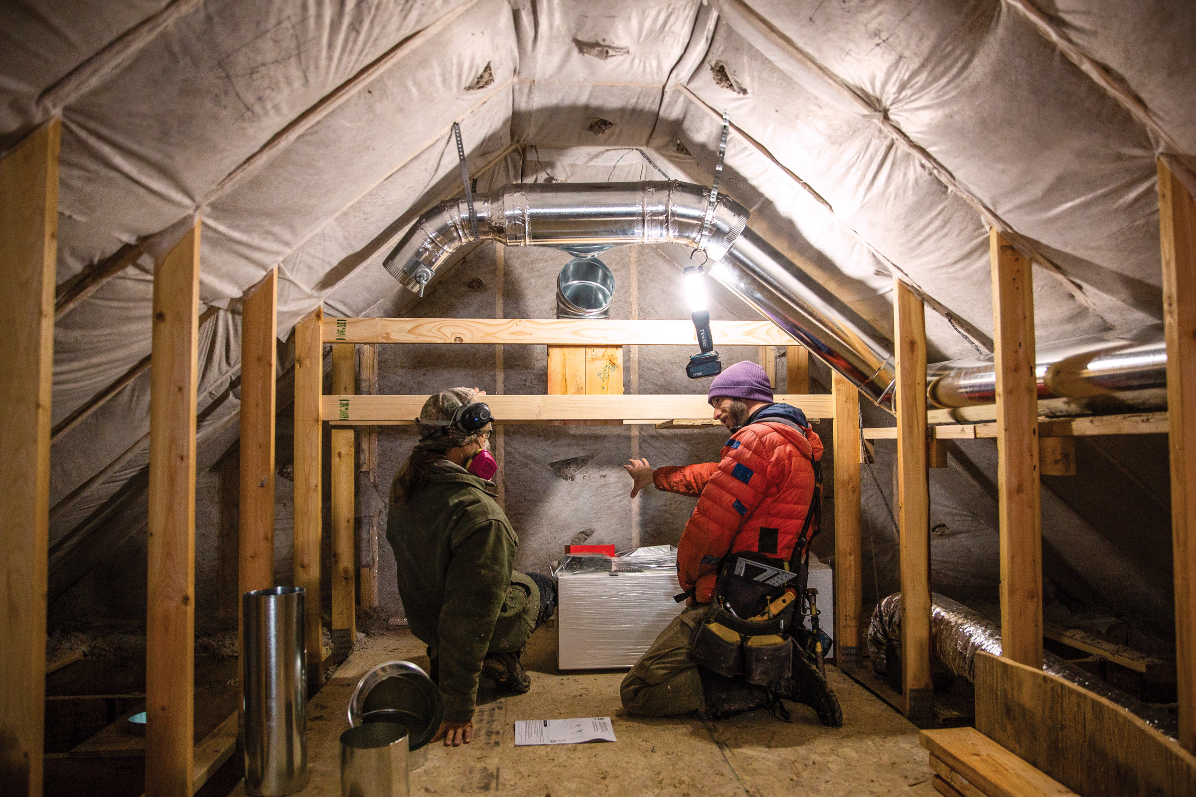 Cillian Liam Barrett and Edward Morrison install a heat pump system in the attic of a new accessory dwelling unit in Crested Butte, Colorado. The town recently passed new energy-efficient building codes.