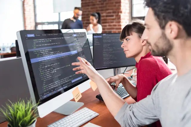 Two students learning about software in front of computer screens