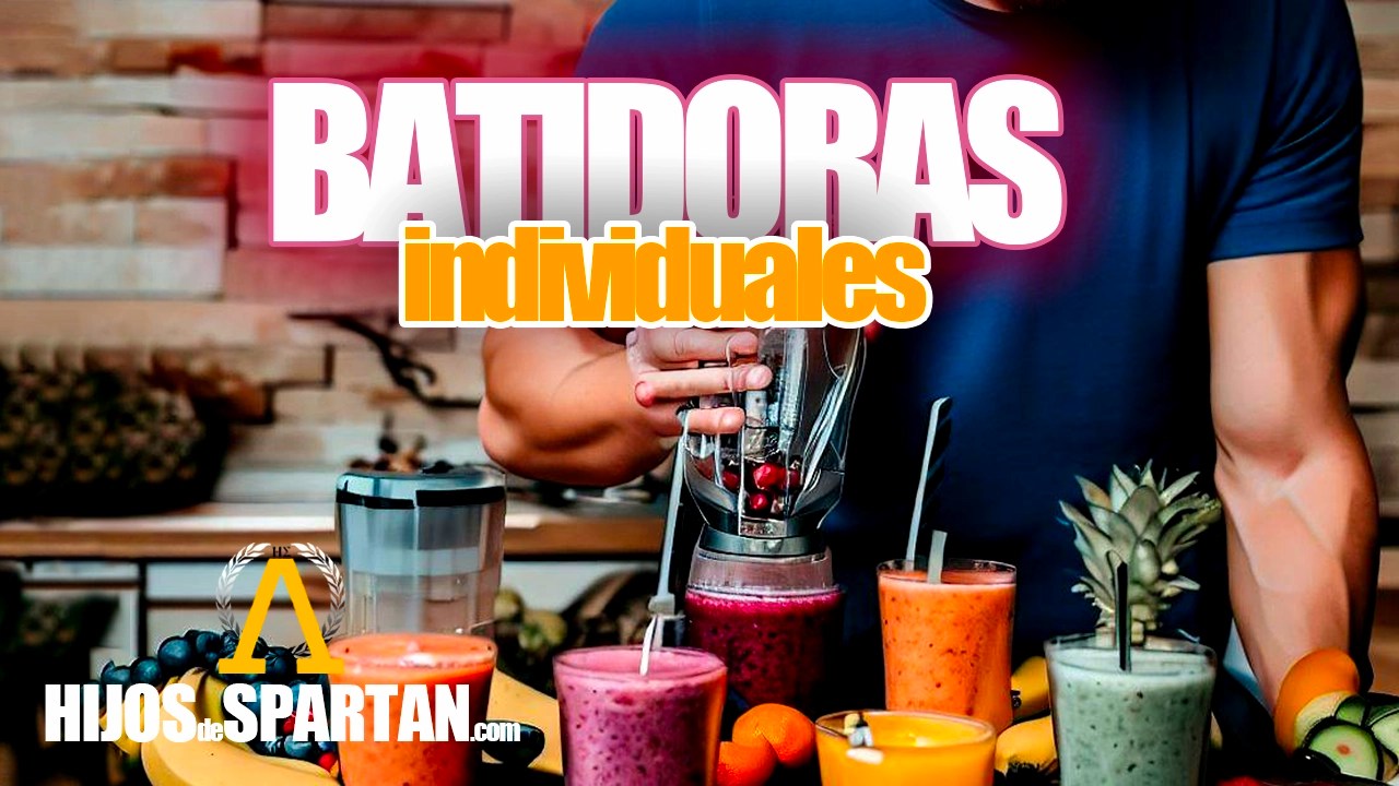 Hombre con camiseta azul rodeado de frutas y batidos de todos los colores mientras lo realiza con el batidor portatil