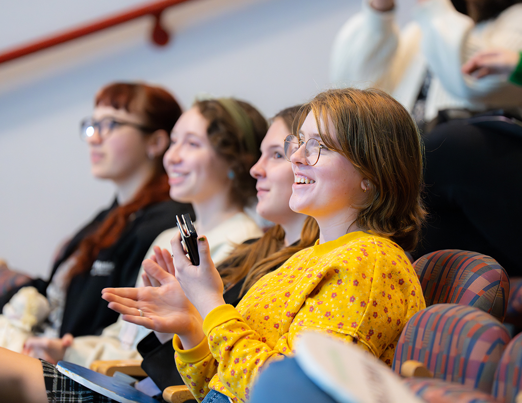 Students in a classroom smiling and listening