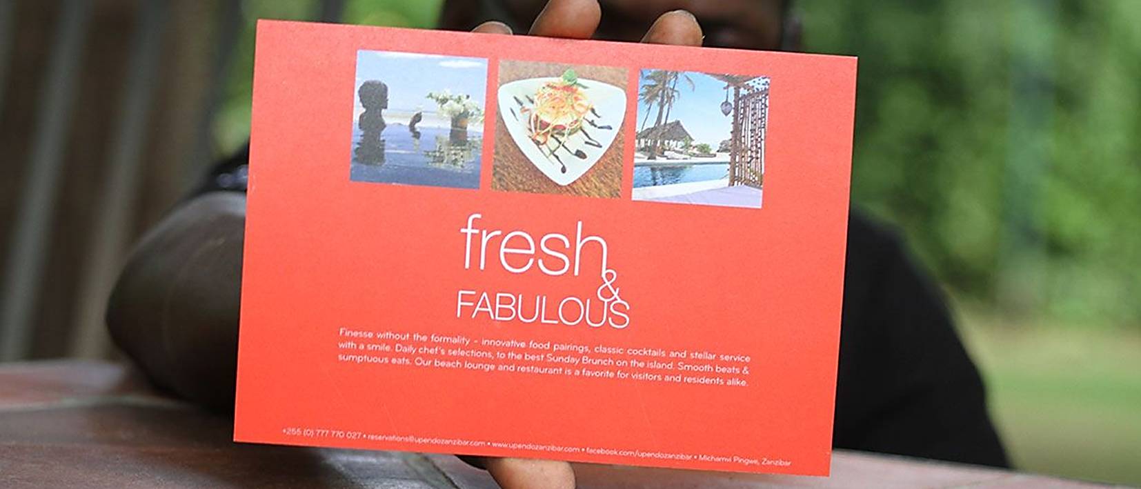 hand holding orange postcard