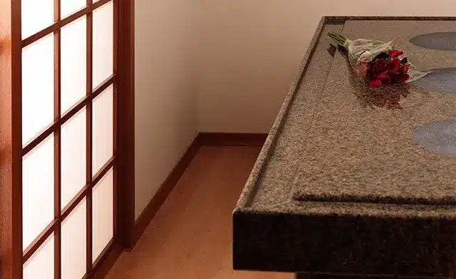 A bouquet of red roses is placed on a granite countertop in a room with wooden flooring and a shoji screen door.