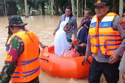 Kapolsek Indra Makmu Ipda Novian Fitra didampingi Bhabinkamtibmas mengevakuasi seorang ibu yang baru melahirkan dalam situasi banjir di Desa Alu Ie Mirah, Kecamatan Indra Makmu, Aceh Timur, Sabtu (8/10)