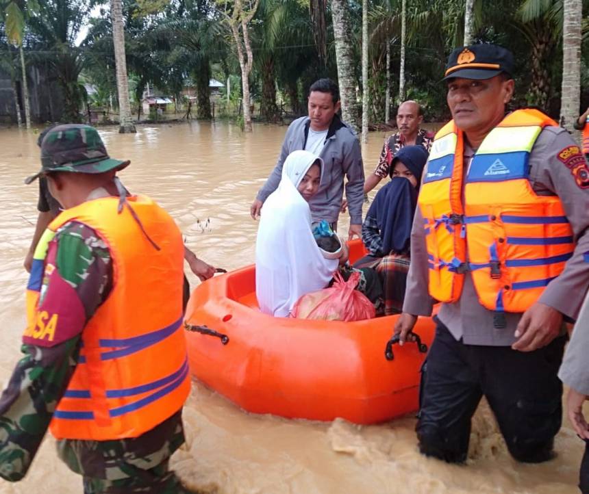 Kapolsek Indra Makmu Ipda Novian Fitra didampingi Bhabinkamtibmas mengevakuasi seorang ibu yang baru melahirkan dalam situasi banjir di Desa Alu Ie Mirah, Kecamatan Indra Makmu, Aceh Timur, Sabtu (8/10)