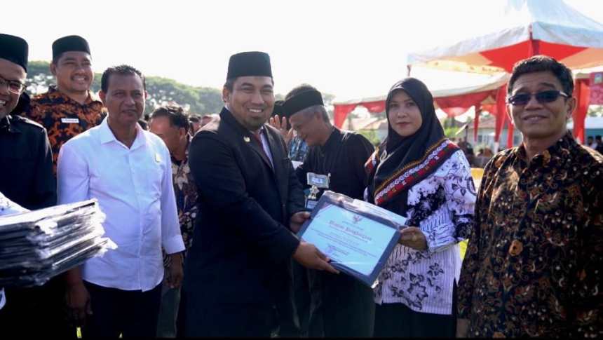 Pj Bupati Aceh Besar Muhammad Iswanto menyerahkan penghargaan kepada guru pada upacara peringatan HGN dan HUT ke-77 PGRI di Lapangan Angkasa Pura, Blang Bintang, Sabtu (26/11)