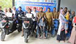 Pj Bupati Aceh Besar Muhammad Iswanto didampingi Kadis Sosial Aceh Besar Bahrul Jamil Anggota DPRK Aceh Besar Mustafa Ishak dan Camat Ingin Jaya, Al Mubarak Akbar foto bersama dengan penerima bantuan motor tiga roda dan kursi roda untuk disabilitas, di gudang Dinsos Aceh Besar, Gampong Pasie Garot, Ingin Jaya, Aceh Besar, Selasa (27/6)