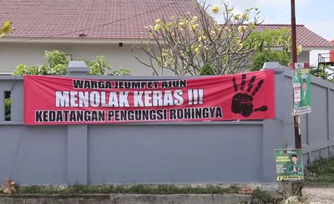 Spanduk dipasang warga yang menolak pengungsi Rohingya dipindahkan ke Markas PMI Aceh di Gampong Ajuen Jeumpet Kecamatan Darul Imarah Aceh Besar