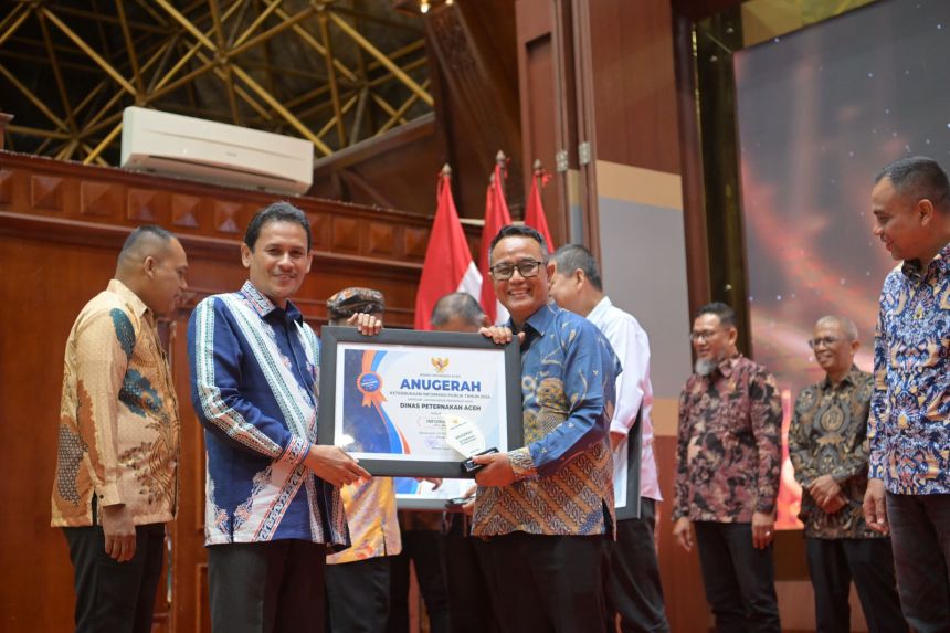 Asisten Perekonomian dan Pembangunan Sekda Aceh Zulkifli, menyerahkan penghargaan keterbukaan informasi publik, di Anjong Mon Mata, Meuligoe Gubernur Aceh, Selasa malam (19/11). (Foto: For Infoaceh.net)