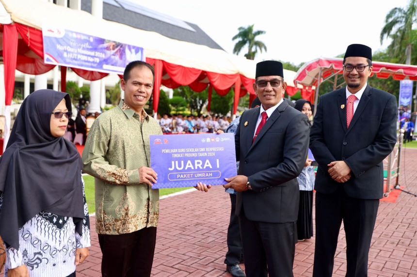 Plt. Sekda Aceh Muhammad Diwarsyah menyerahkan hadiah umrah kepada Guru dan Tendik (GTK) berprestasi, pada peringatan Hari Guru Nasional 2024 di halaman Kantor Gubernur Aceh, Kamis (5/12). (Foto: For Infoaceh.net)