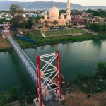 Jembatan gantung yang menghubungkan Gampong Lambhuk Kecamatan Ulee Kareng dan Gampong Lamseupeung Kecamatan Lueng Bata, Banda Aceh dengan latar belakang Masjid Haji Keuchik Leumiek. (Foto: Ist)