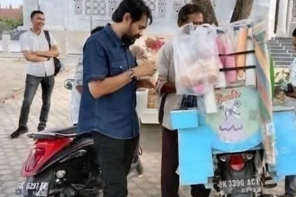 Gubernur Aceh Muzakir Manaf atau Mualem saat jajan es krim di depan sebuah masjid di Aceh yang penjualnya menggunakan sepeda motor berplat BK. (Foto: Ist)