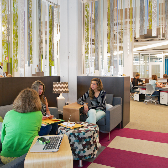 A group of young women working sitting in a semi-private area of a coworking space in Winston-Salem.