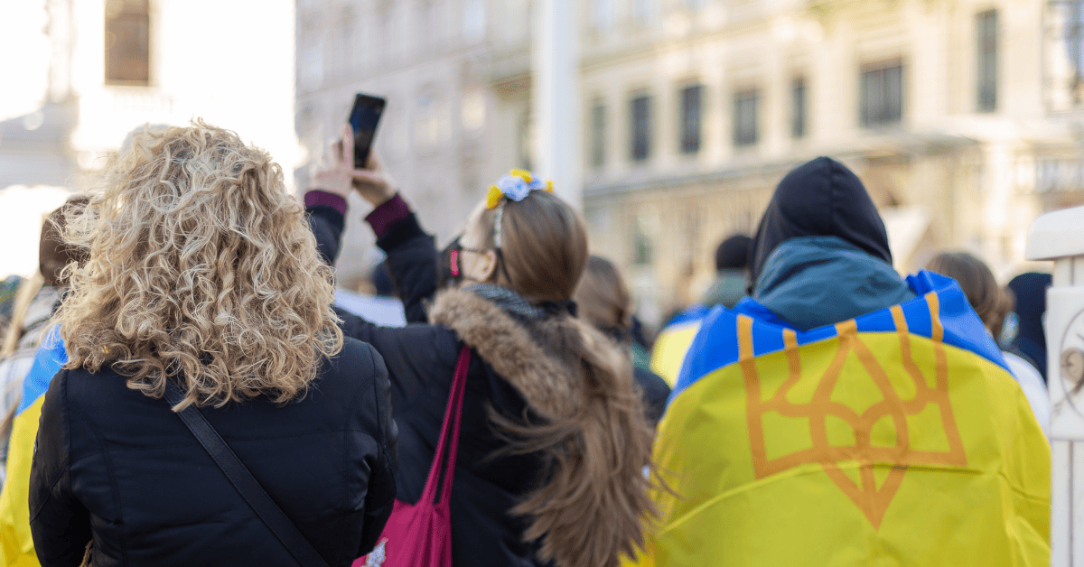 Woman uses phone to record scenes whilst man wears Ukraine flag