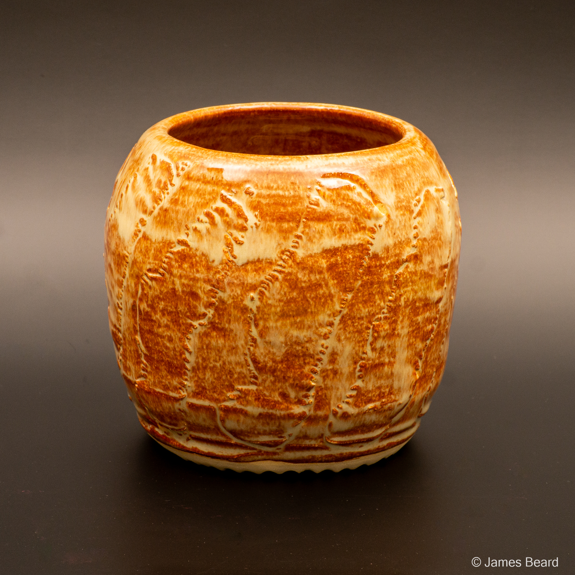 A warm red and white, textured ceramic vessel on a dark background.