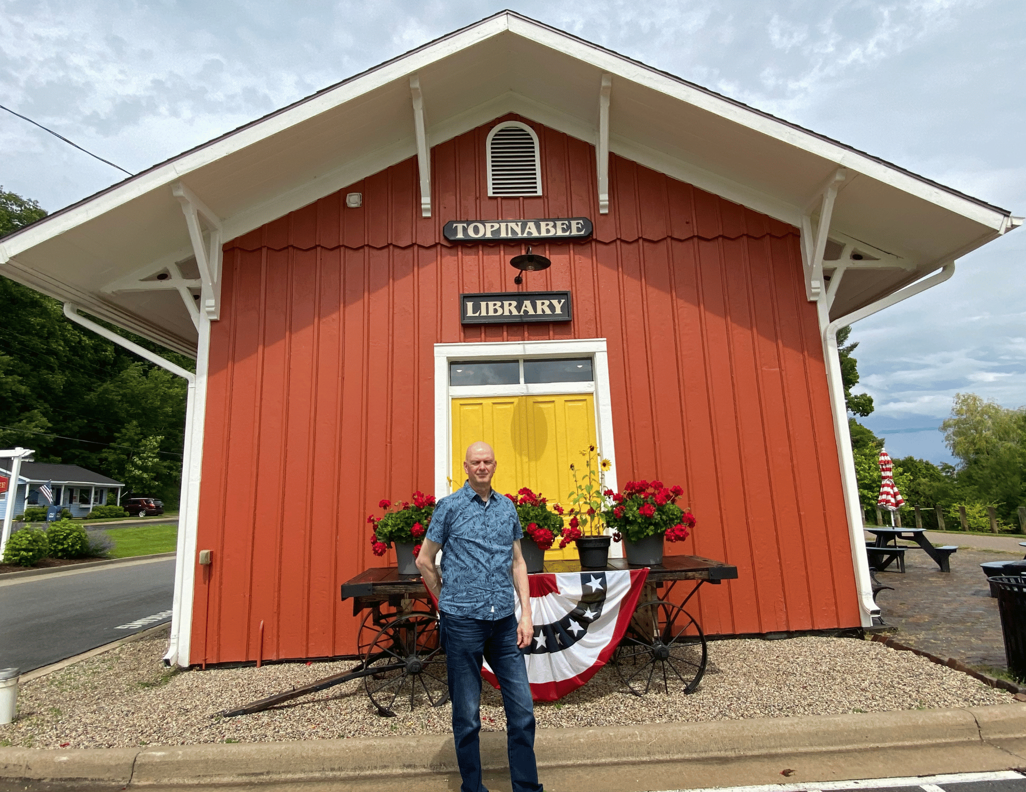 Entrepreneur John Smyk stands in front of a refurbished historical library in Topinabee, MI to promote creating inspirational entrepreneurial confidence.