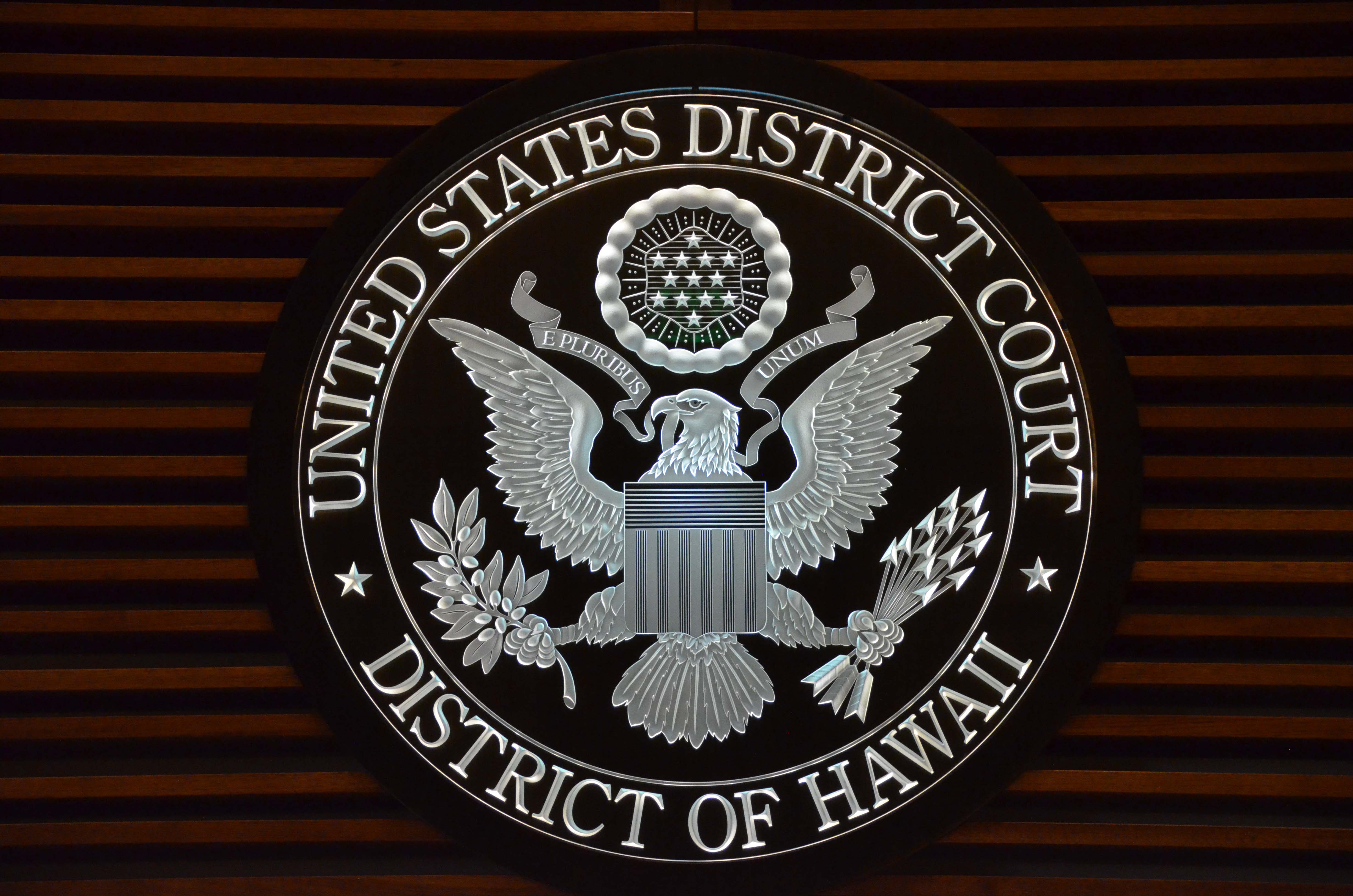 The seal for the United States District Court District of Hawaii. The seal includes a bald eagle holding olive leaves in one talon and arrows in the other talon. A ribbon in its mouth reads, “E Pluribus Unom”