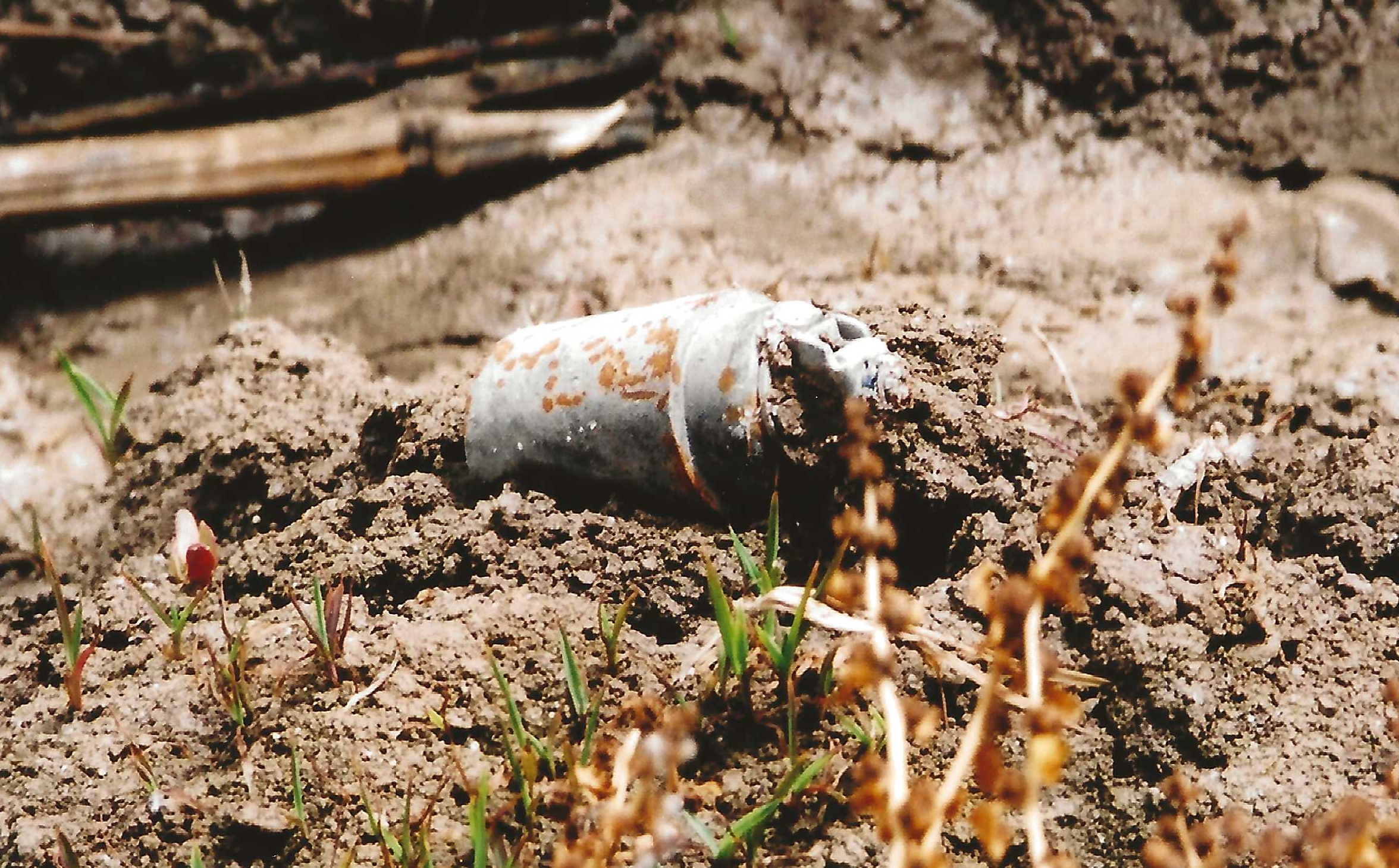 A unexploded DPICM submunition is shown in a dirt field.