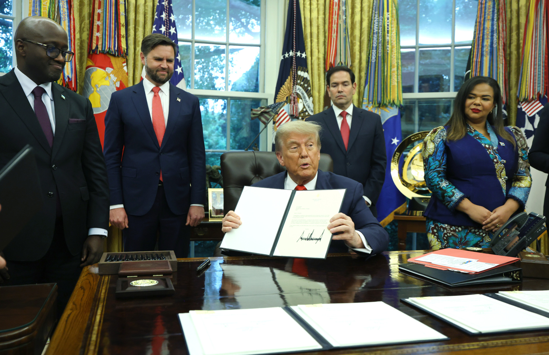 U.S. President Donald Trump signs a letter of congratulations as he meets with Minister of Foreign Affairs and Cooperation of Rwanda Olivier Nduhungirehe and the Foreign Minister of the Democratic Republic of the Congo Thérèse Kayikwamba Wagner