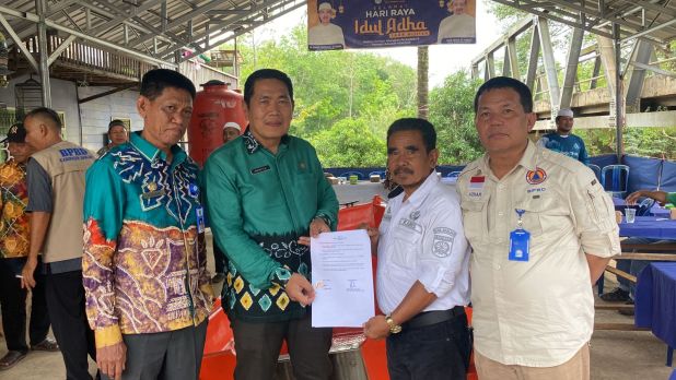 Bantuan diserahkan simbolis Kepala BPPD Kabupaten Banjar Warsita kepada Pambakal Desa Pengaron, Supiannoor, Kamis (13/7/2023). (Foto: Kominfo Kabupaten Banjar/Katajari.com)