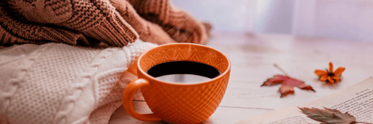 Photo of sweaters and a cup of coffee on a wooden table