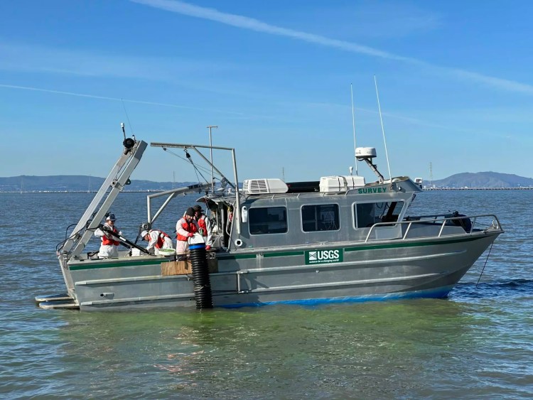 The RS Snavely conducts side scan sonar of the bay bottom The RS Snavely conducts side scan sonar of the bay bottom and distributes the neon green tracers (see water) over the placement area. Photo: USGS