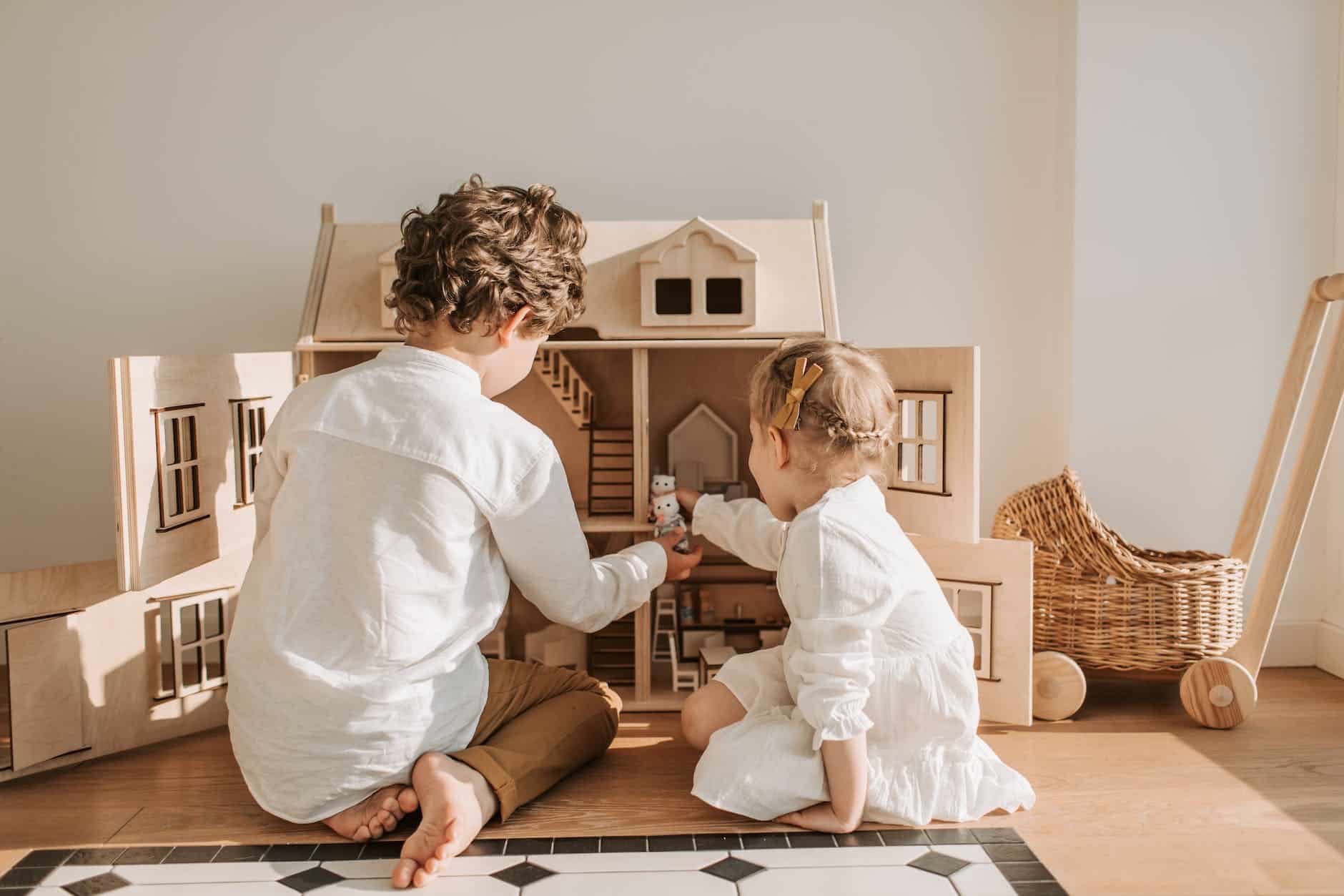 back view of kids playing with a dollhouse