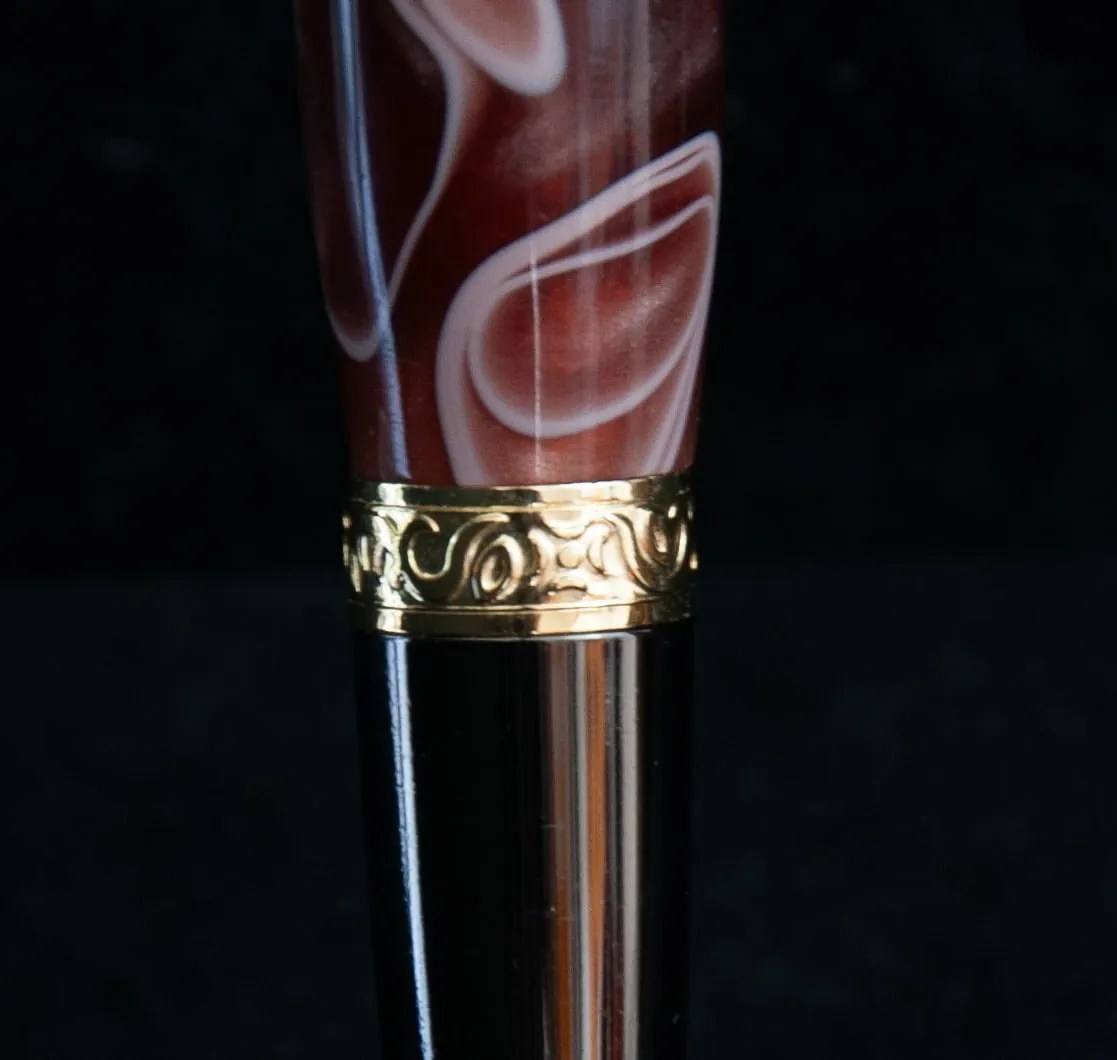 Stylo bille rechargeable (mine type parker). Mécanisme plaqué or et titane noir habillé d' une résine marron et blanche. Bague cenrale finement ciselée.