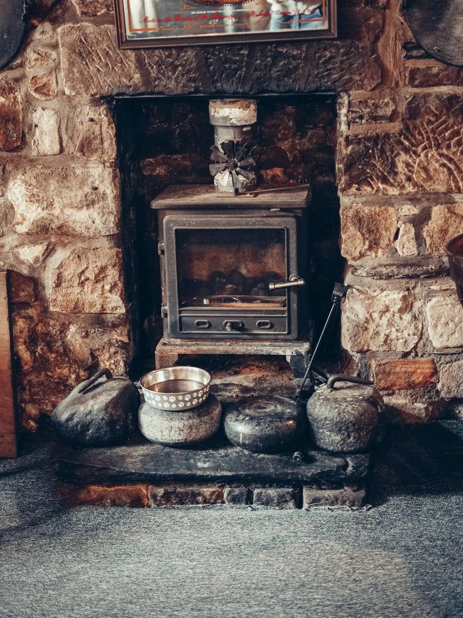 Cheminee de pierre et poele du Settle Inn, a Stirling : avec la penombre de la salle, elle donne au pub son allure de refuge.