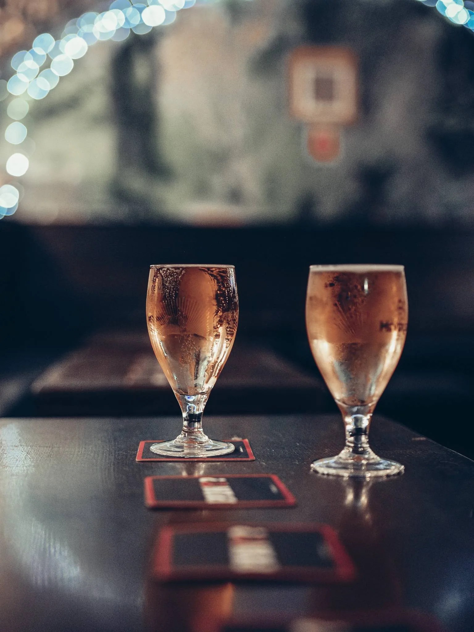 Deux verres de biere sur une table de bois du Settle Inn, a Stirling, dans l'ambiance tamisee du pub.