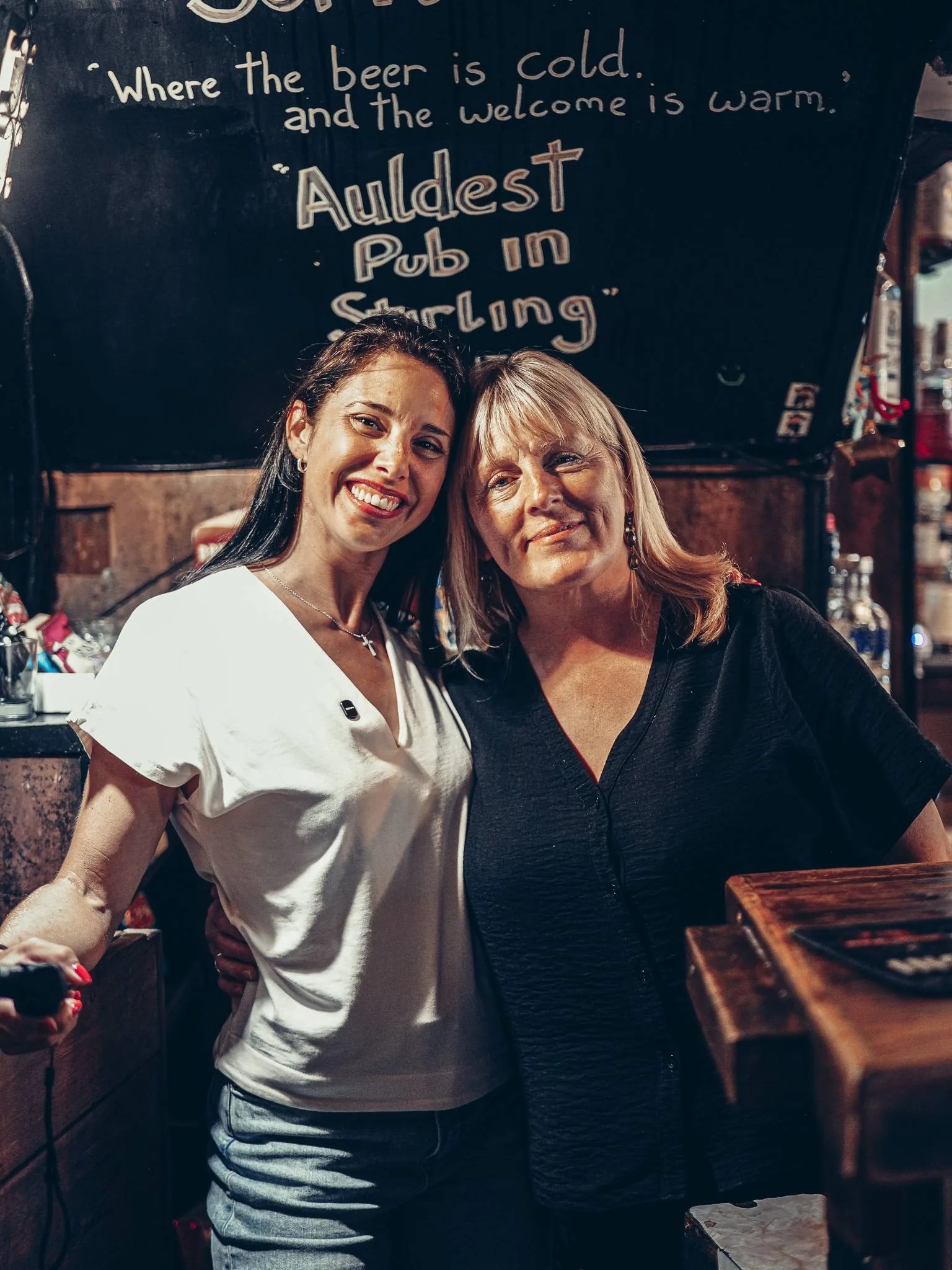 Caroline avec une habituee du Settle Inn, devant le comptoir, a Stirling : l'accueil des habitues du pub est alle jusqu'a la bise.