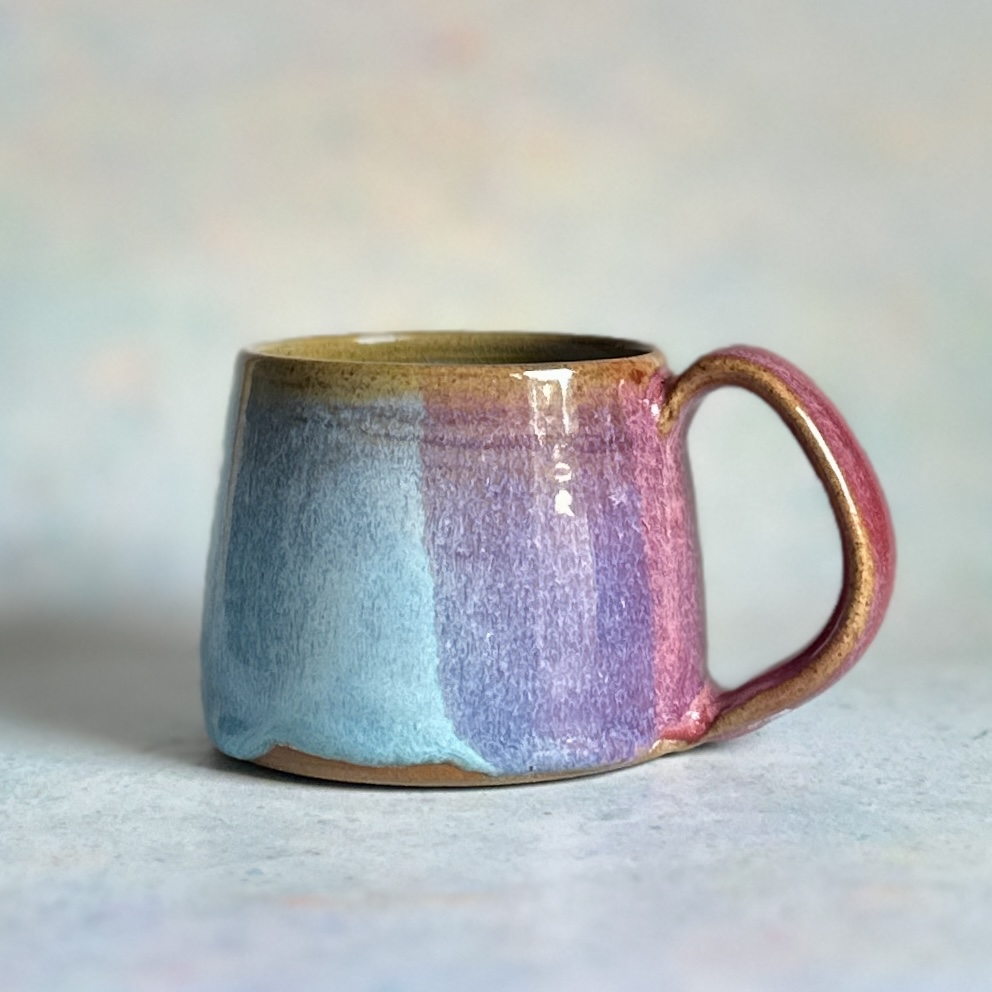 Handcrafted ceramic coffee cup in Aurora glaze – pink, lavender, blue, and golden tones | Emberglow Collection