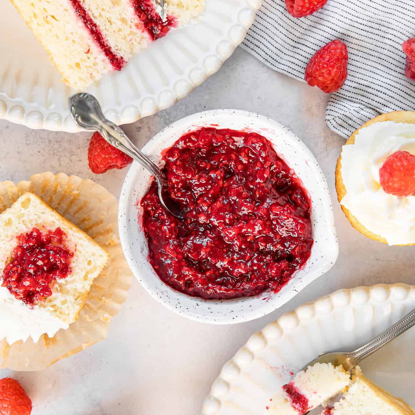 A bowl of raspberry cake filling with cupcakes and a cake next to it.