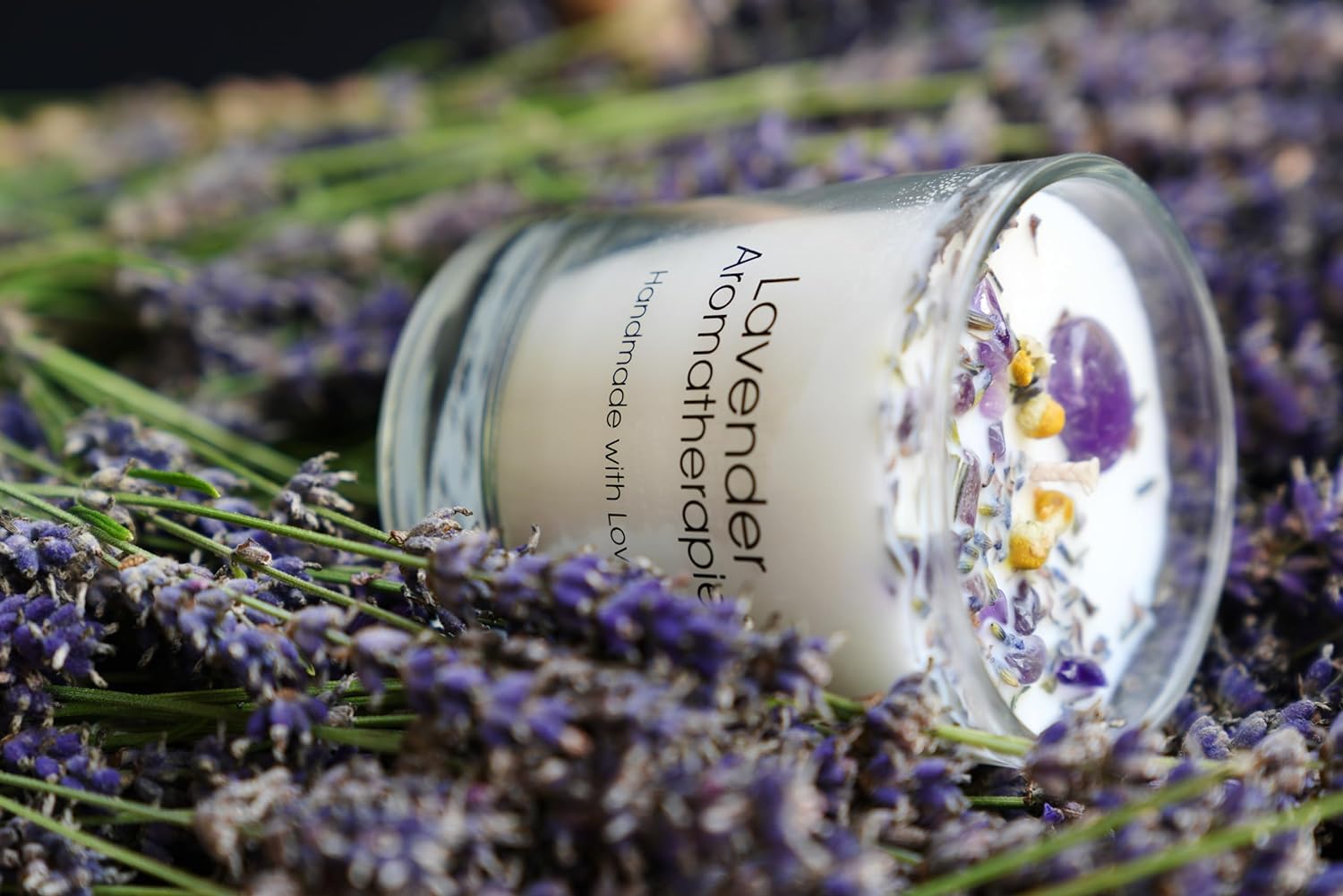 Lavendel Duftkerze, liegend in einem Bett aus frischem Lavendel, schafft eine beruhigende und entspannende Atmosphäre