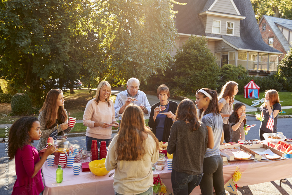 Neighbours talk and eat around a table at a block party