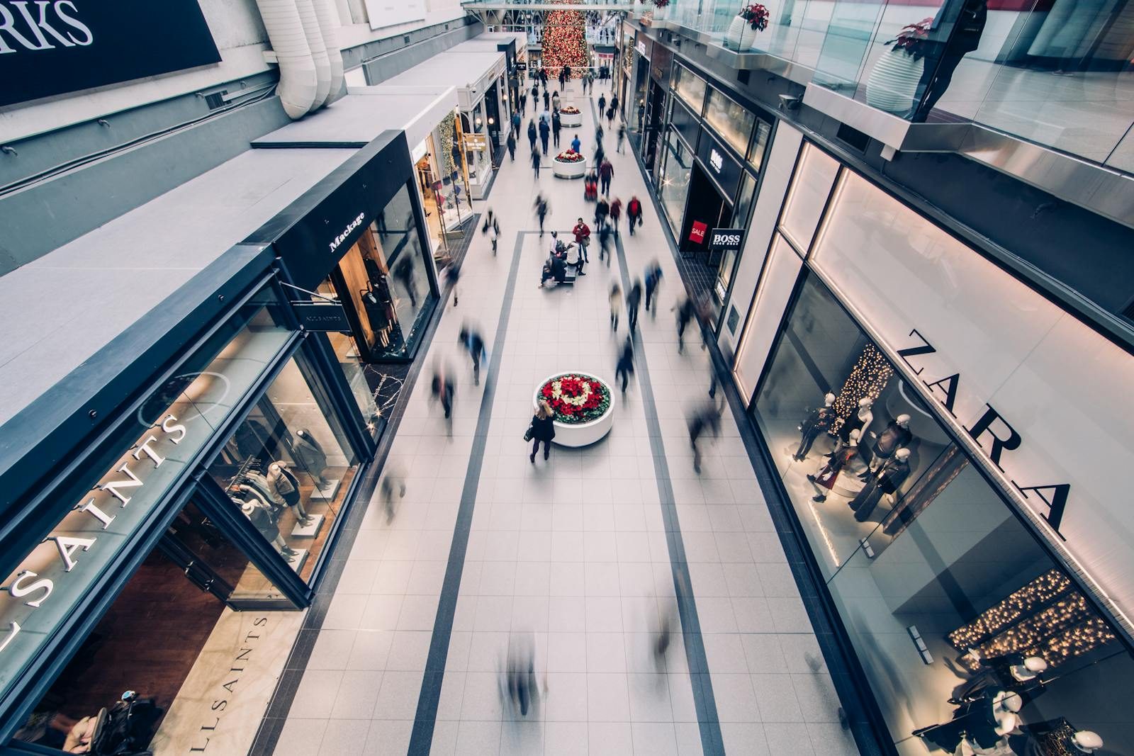 A vibrant scene capturing a busy shopping mall with modern stores and diverse shoppers on the move.