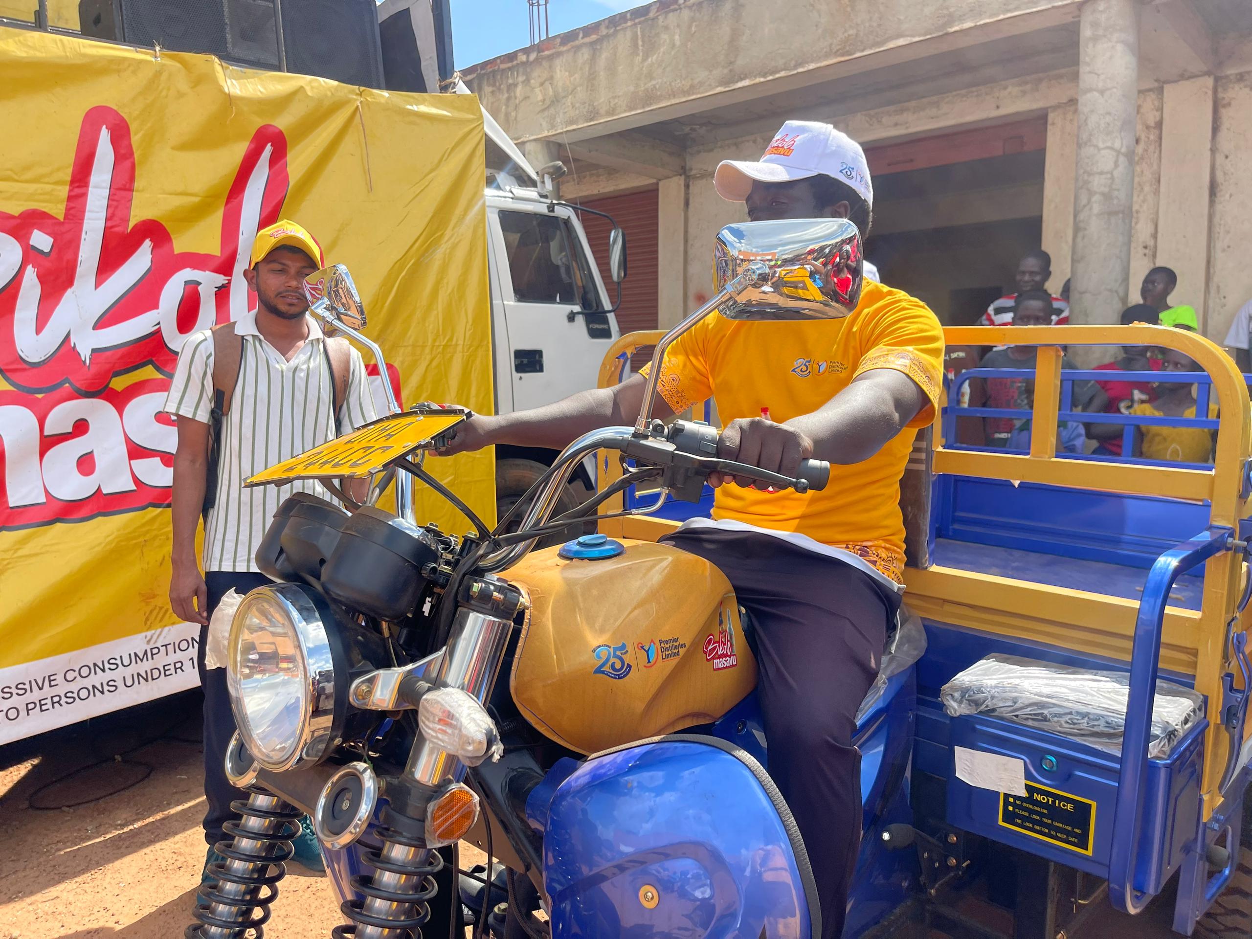 Emmanuel Ogwal (R) receives a brand new Tuk Tuk after winning from the Bikole Masavu Promotion by Premier Distilleries Limited.