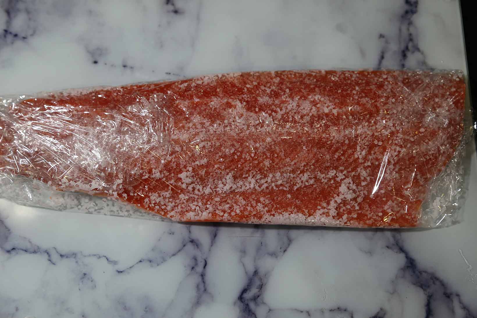 Covering salmon with plastic wrap