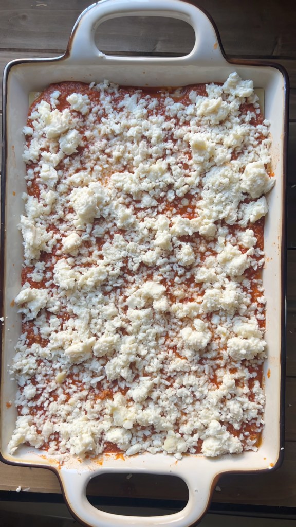 Assembled lasagna covered with a generous layer of shredded mozzarella