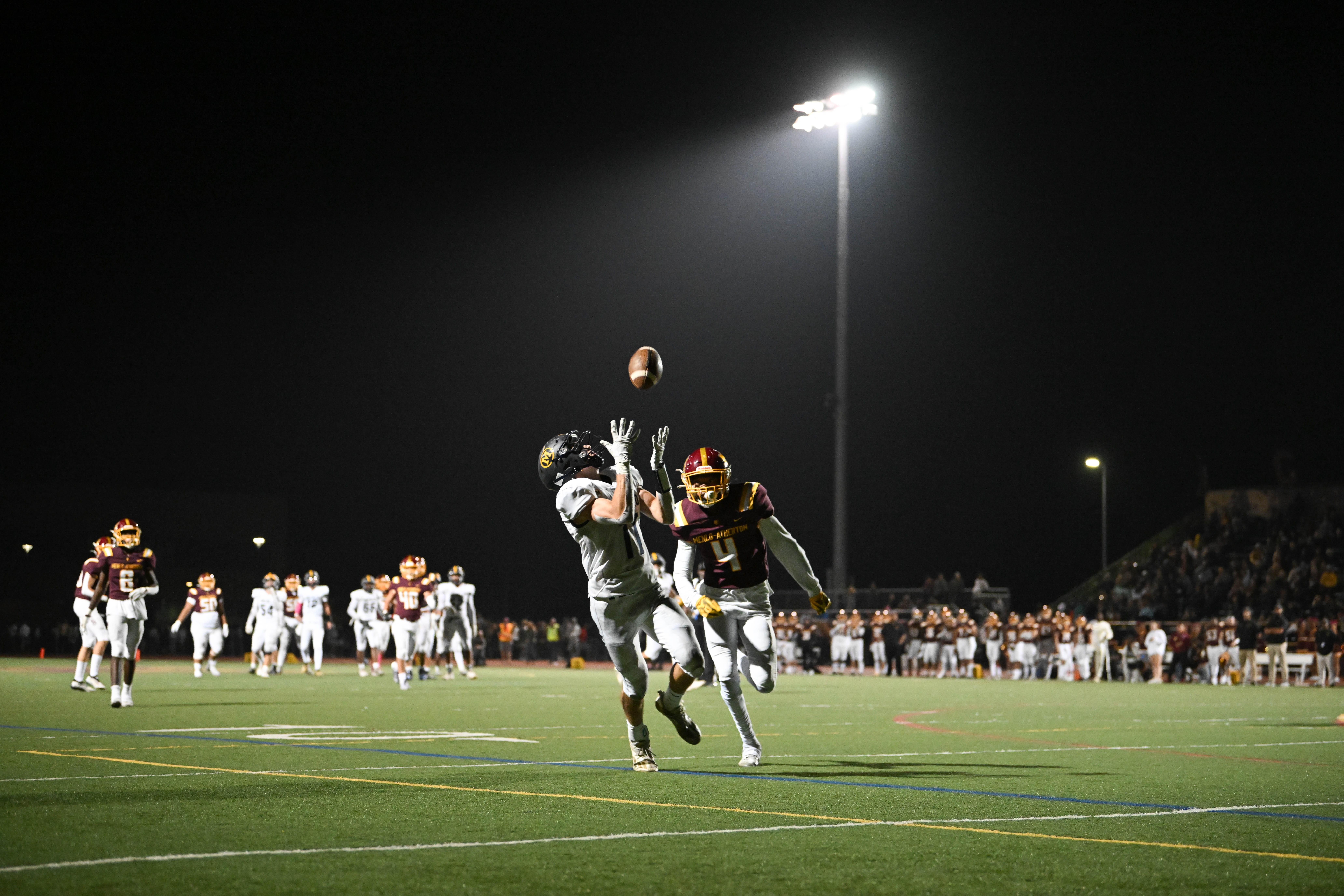 Menlo's Robby Enright (11) catches a pass while being guarded by Menlo Atherton's Cameron Johnson (4) during their game on Oct. 21, 2022, in Atherton, Calif. (Thien-An Truong for Bay Area News Group)