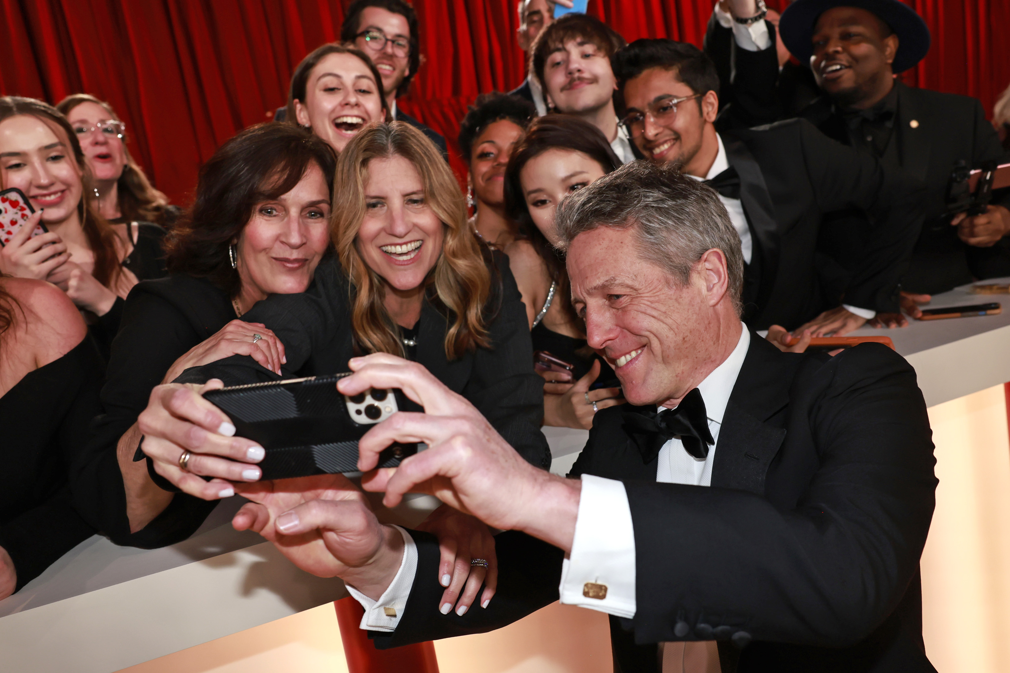 HOLLYWOOD, CALIFORNIA - MARCH 12: Hugh Grant takes a selfie with a fan during the 95th Annual Academy Awards on March 12, 2023 in Hollywood, California. (Photo by Emma McIntyre/Getty Images)