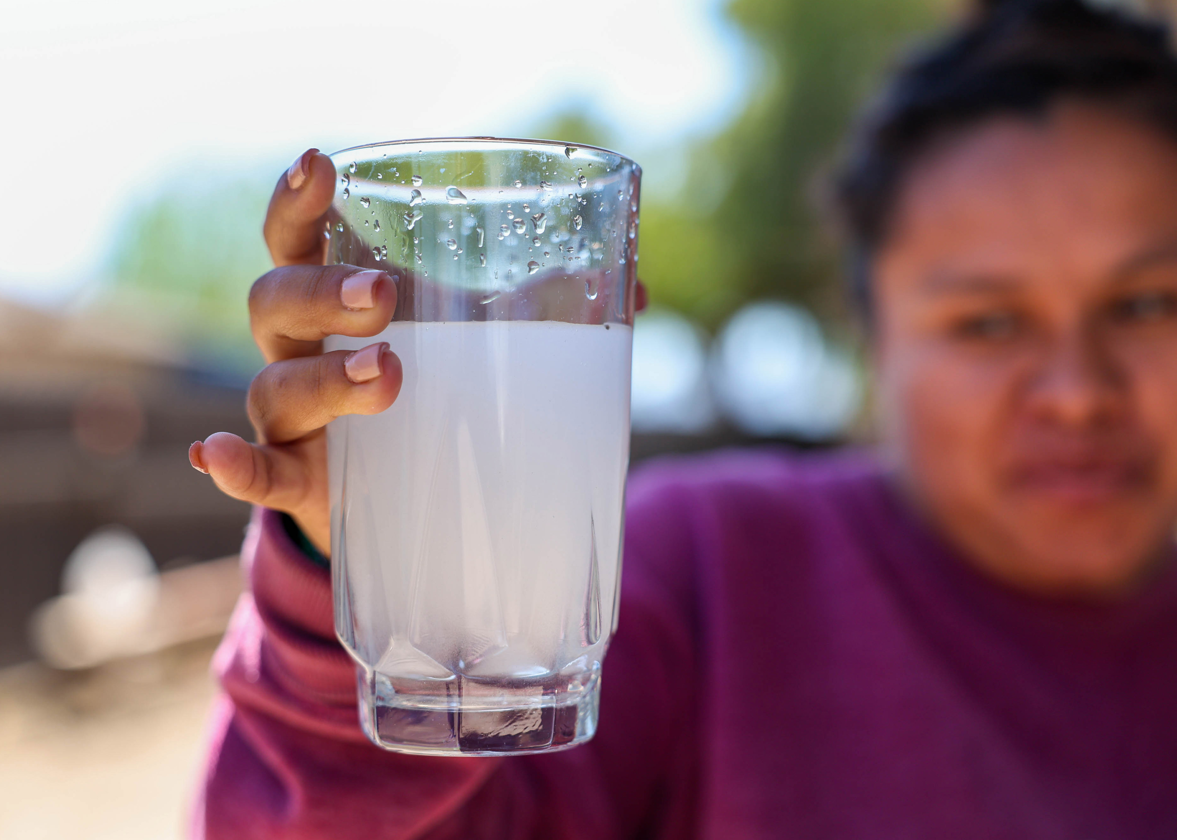 Andrea Silva holds a glass of cloudy water from the faucet at her home in San Lucas, Calif., on Thursday, April 14, 2023. (Ray Chavez/Bay Area News Group)