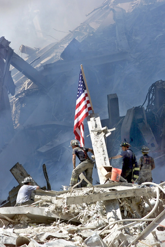 A NYC firefighter raises the American flag on the Ground Zero pile in the days after the 9/11 attacks. (Mike Adaskaveg/Boston Herald)