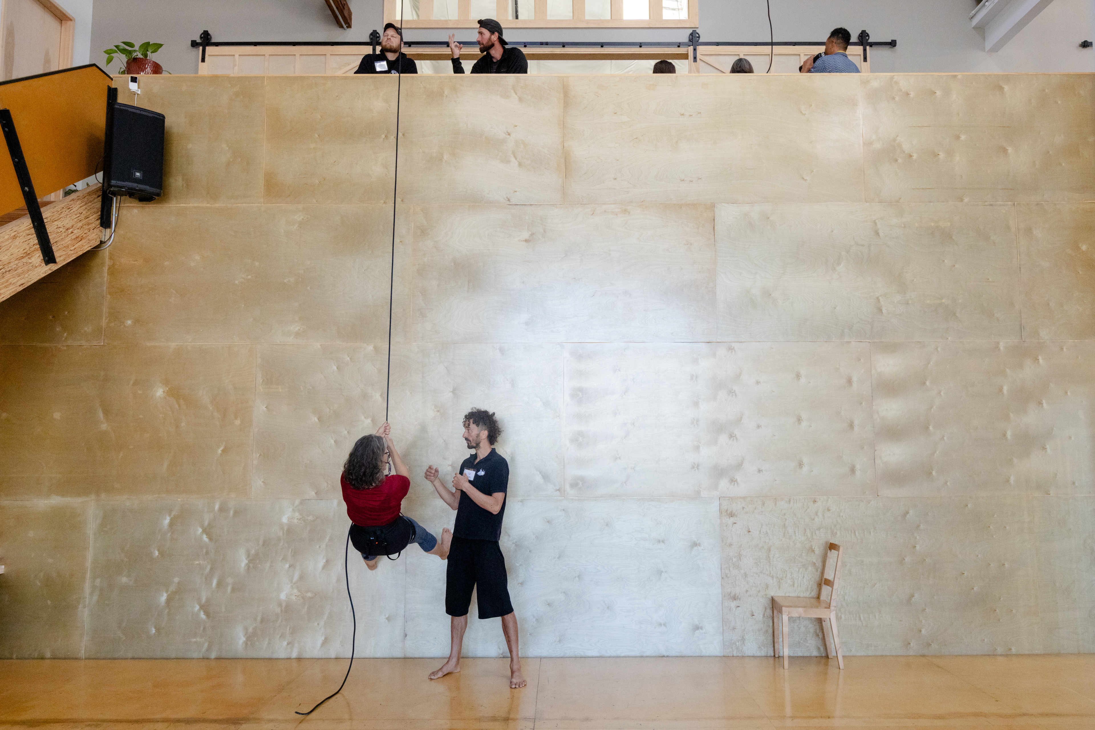 OAKLAND, CA - NOVEMBER 12: Roel Seeber (center) instructs a student hanging from a rope attached to a harness during a flight test vertical dance lesson at the BANDALOOP open house at their studio space in Oakland, Calif. on Nov. 12, 2023. BANDALOOP is a renown vertical dance troupe, that have performed their aerial mid-air performances on international landmarks around the world. (Douglas Zimmerman/Special to the Bay Area News Group)