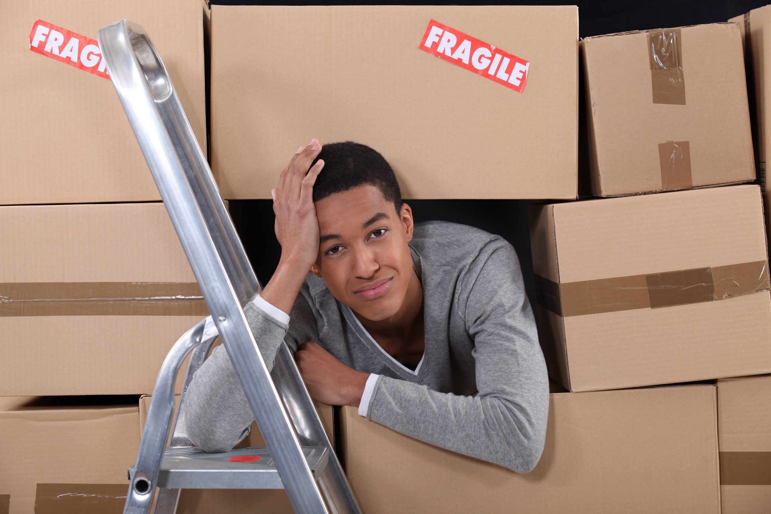 young man surrounded by boxes moving into a new apartment
